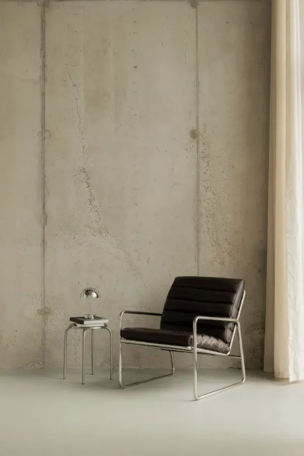 Opnamehoek van Atelier Collective met betonwand, fauteuil, bijzettafel en gordijn