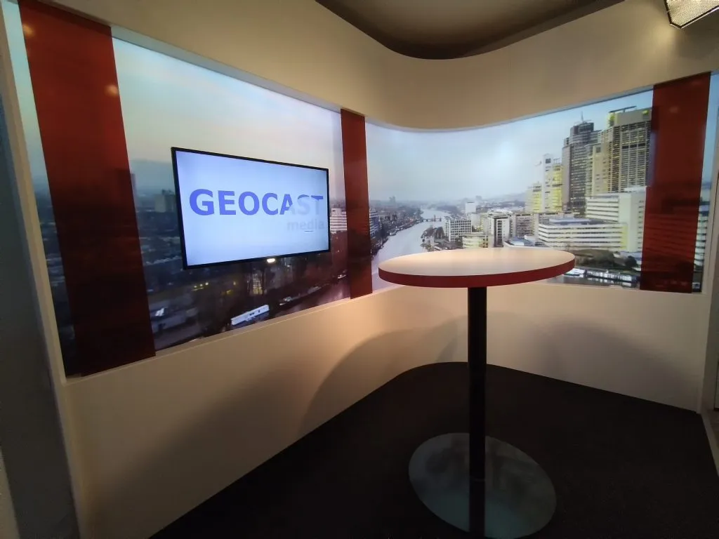 Eigen CorpTV/GEOCAST-studioset in Amsterdam Oost met ovale tafel, scherm en skylineachtergrond