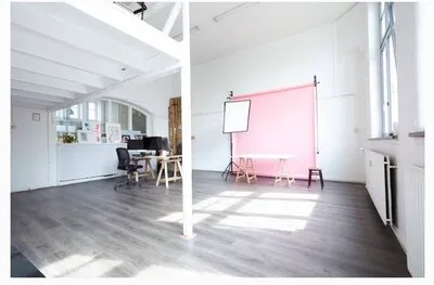 Eigen fotostudio van Elisa Smook met roze achtergrond, verlichting, werkplekken en open vloer