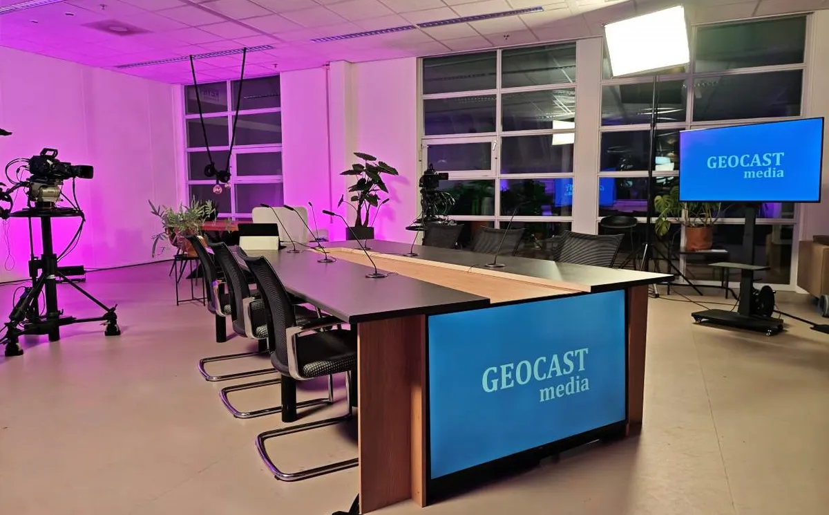 Eigen GEOCAST-studioruimte in Leeuwarden met talkshowtafel, stoelen, camera en ramen