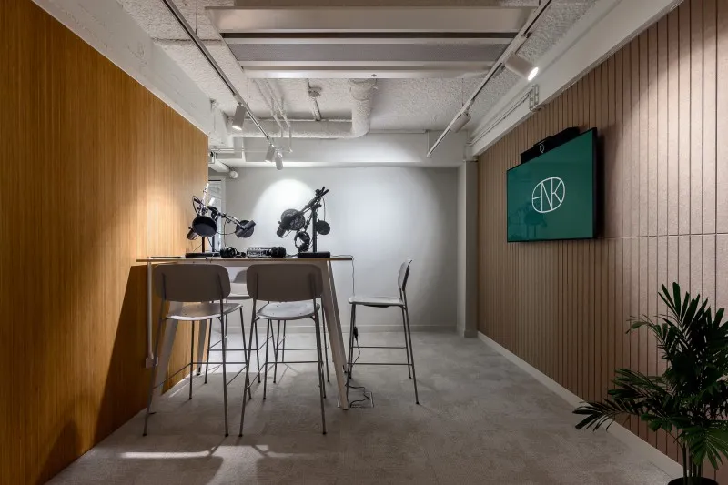 Eigen podcaststudio van HNK Rotterdam met tafel, microfoons en zitmeubilair