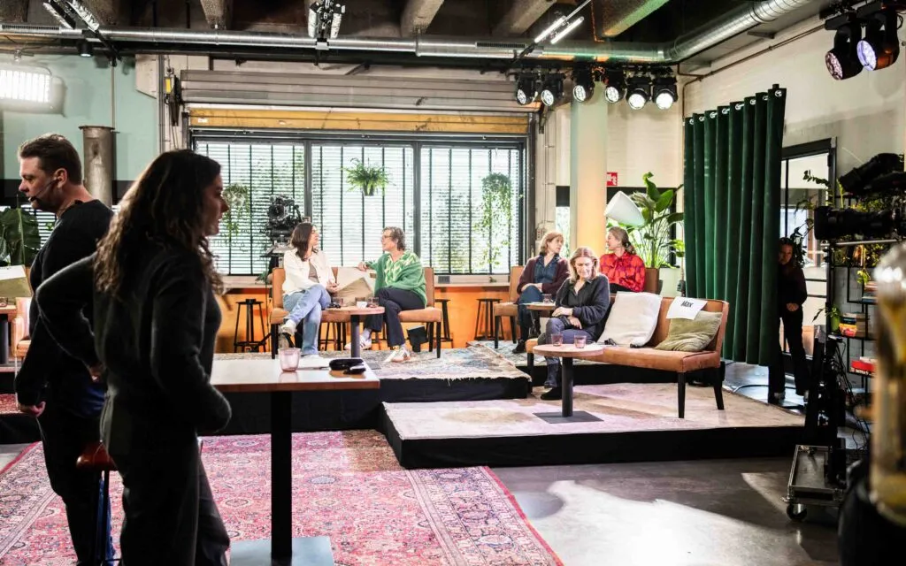 Café-opnamesetting van Podcast District met zithoeken, podium, camera’s en verlichting