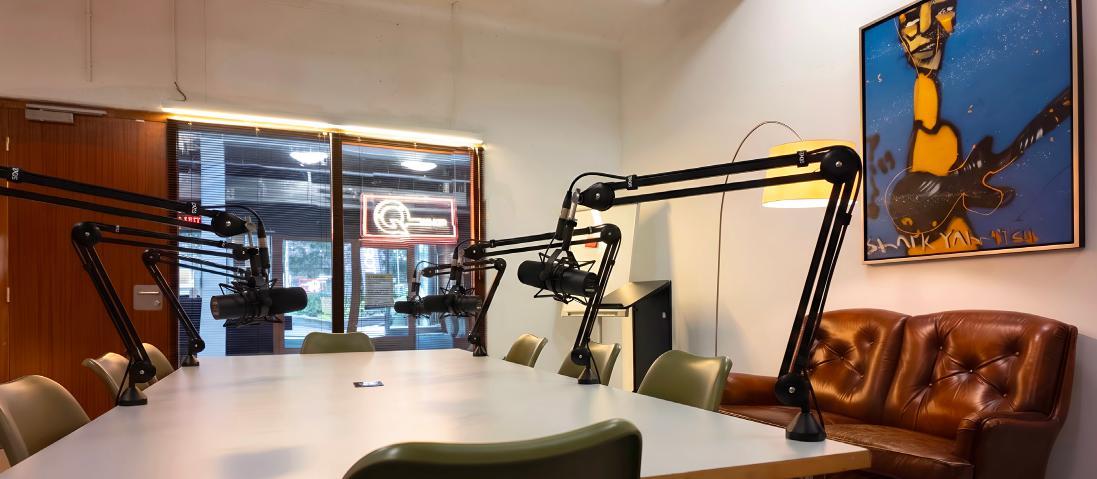 Podcastruimte Atrium van Q-Factory met opnametafel, meerdere microfoons en stoelen