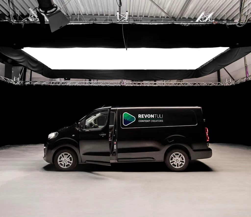 Revontuli-bedrijfsbus onder een grote lichtconstructie in de filmstudio