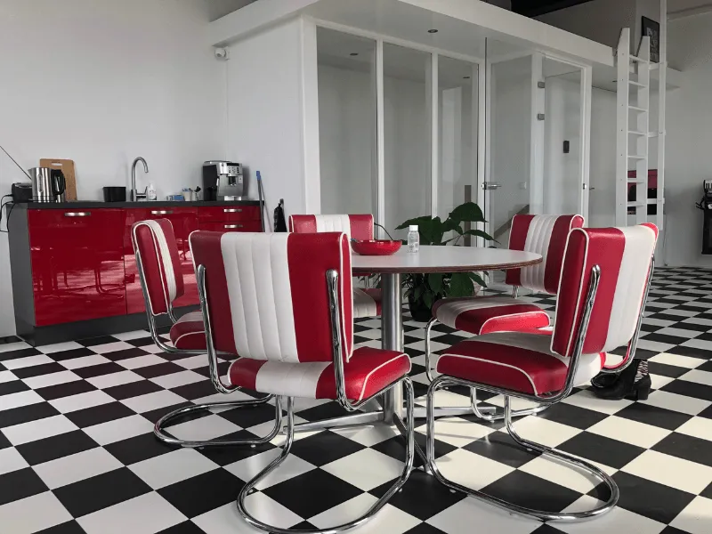 Bovenruimte met tafel, dinerstoelen, keukenblok en zwart-witte vloer